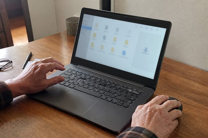크롬으로 받은 파일의 위치를 찾는 중장년 사용자의 Windows 노트북